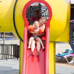 Mama met kids van de zwembadglijbaan